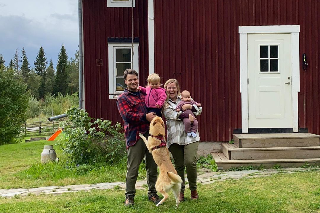 Glückliche Auswanderer-Familie vor ihrem roten Schwedenhaus.